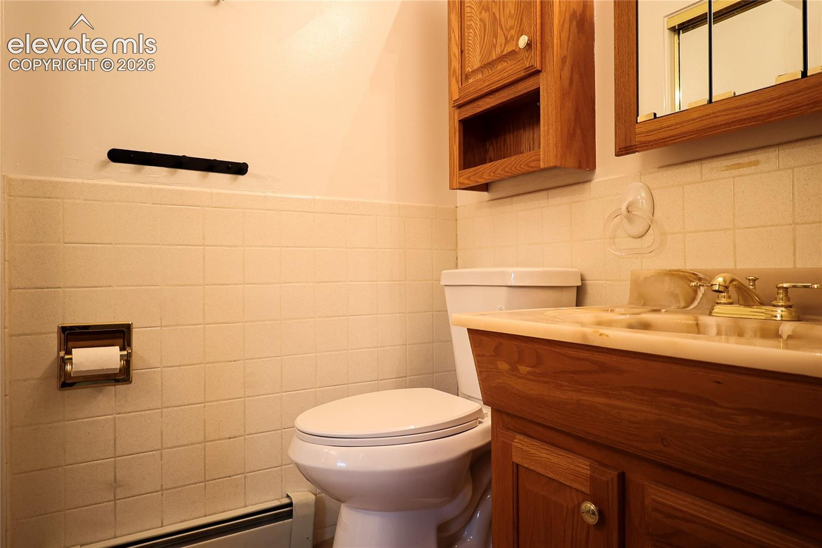 Small bath in bed 2 built-in vanity with wood-finish cabinetry, integrated sink, and brass-tone fixtures