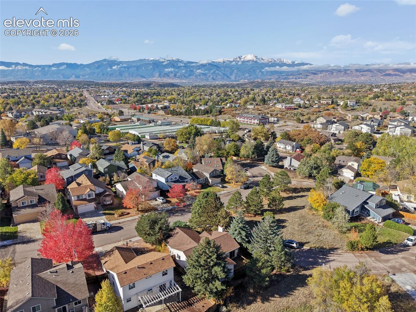 Aerial perspective featuring mature trees, established landscaping, and a prominent mountain backdrop