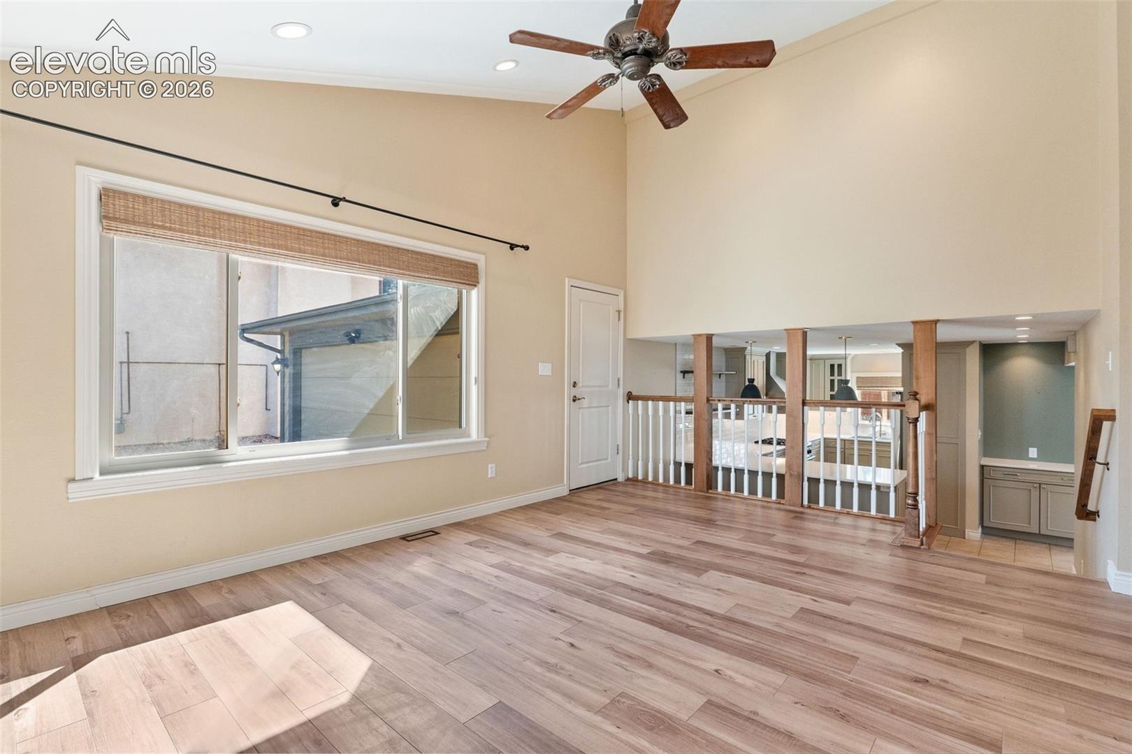 Vaulted ceilings, wood-finish flooring, recessed lighting, ceiling fan, and white spindle railing