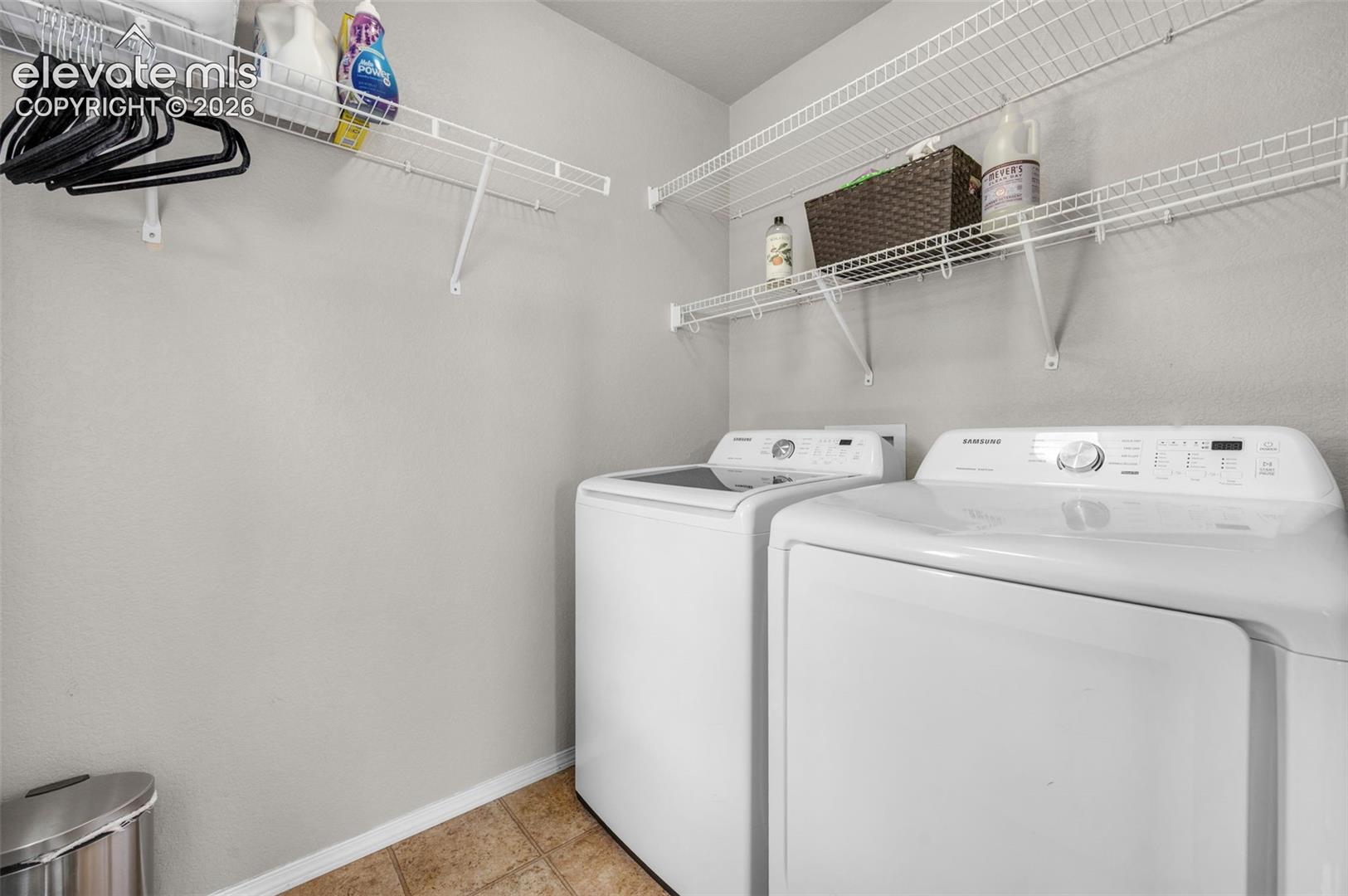 Dedicated laundry on the upper floor  featuring wire shelving, neutral wall paint, and durable tile flooring