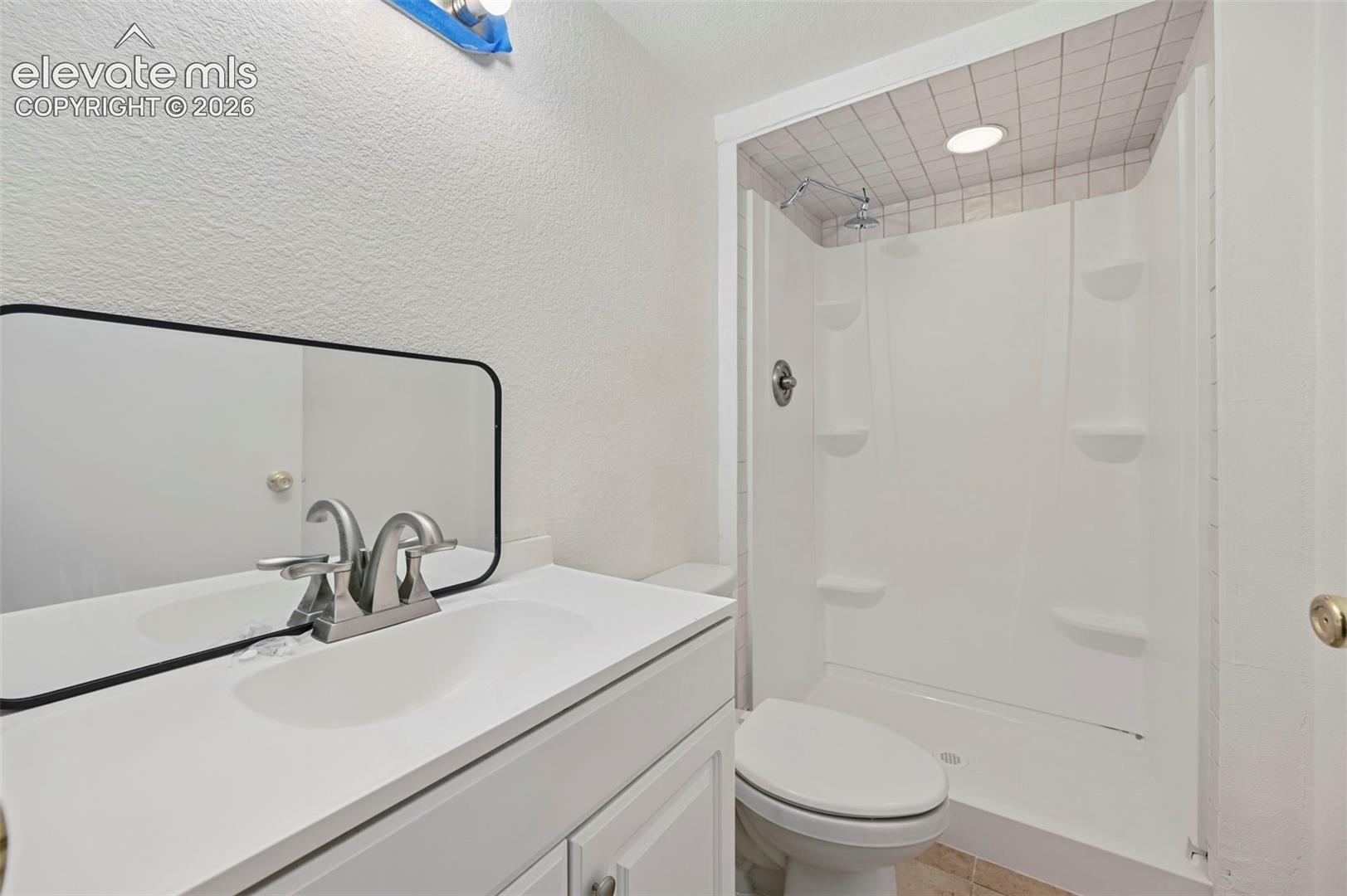 White vanity with integrated sink, brushed nickel faucet, and frameless mirror