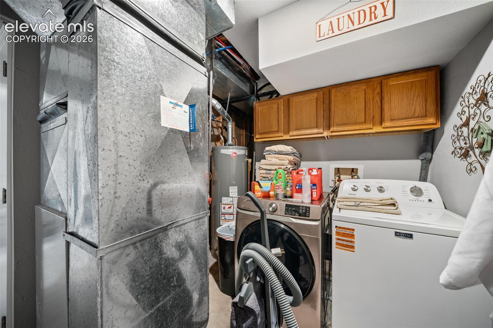 Dedicated utility area featuring overhead wood-finish cabinetry, a laundry hookup, and exposed galvanized ductwork