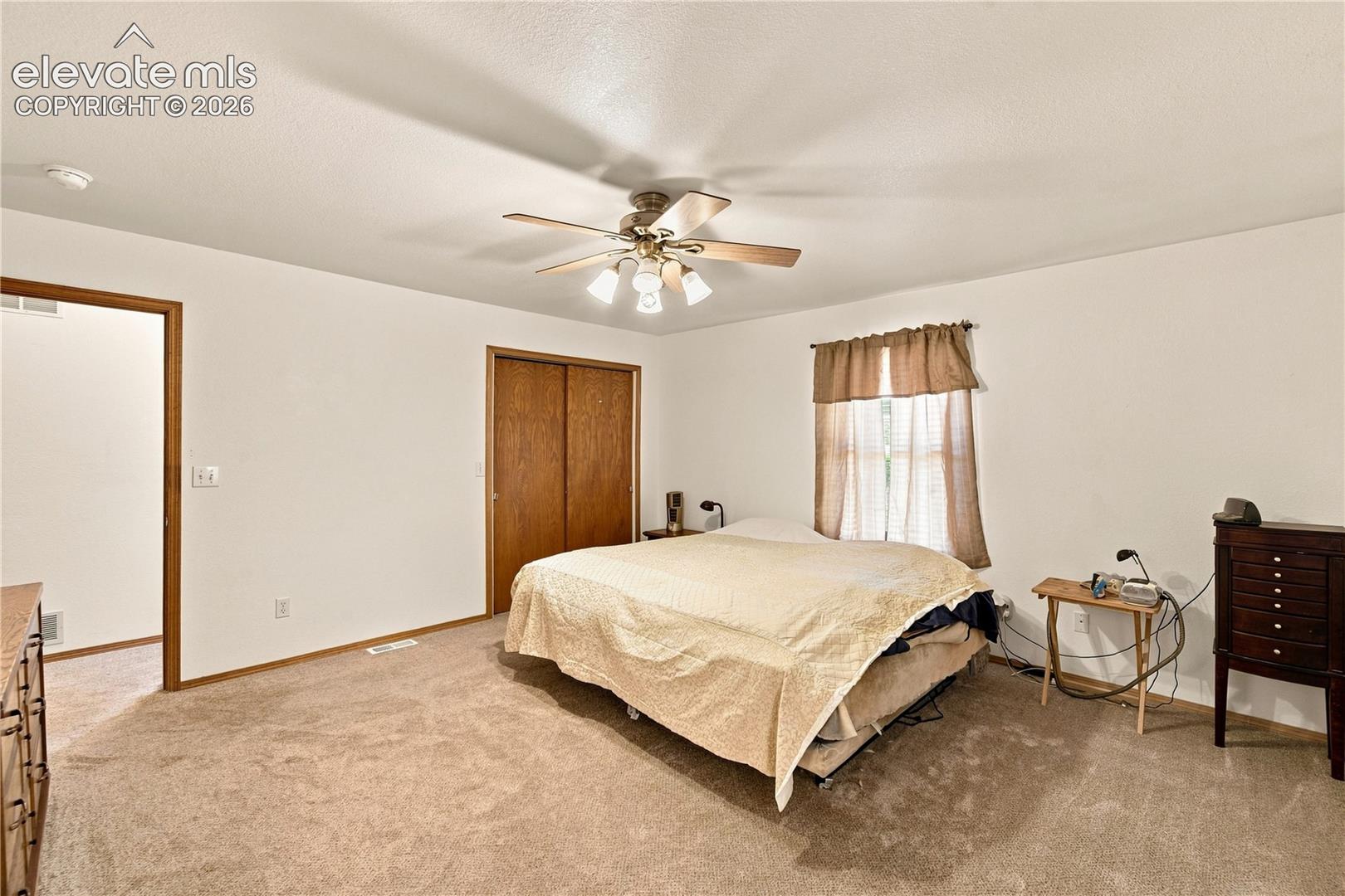 Carpeted flooring, ceiling fan with integrated lighting, wood-finish bi-fold closet doors, and wood-finish trim throughout