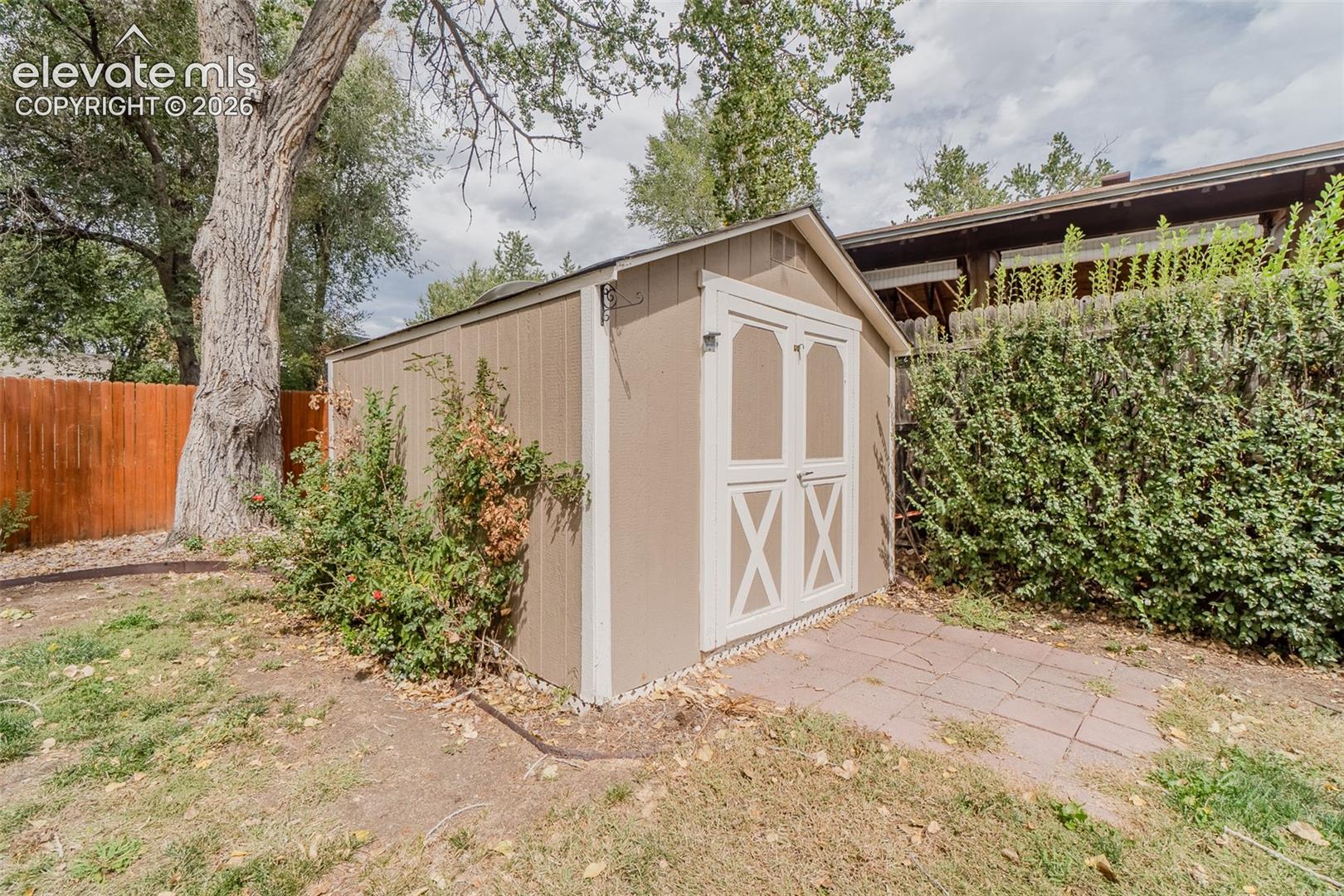 Outdoor storage shed with double doors, wood siding, and an asphalt shingle roof