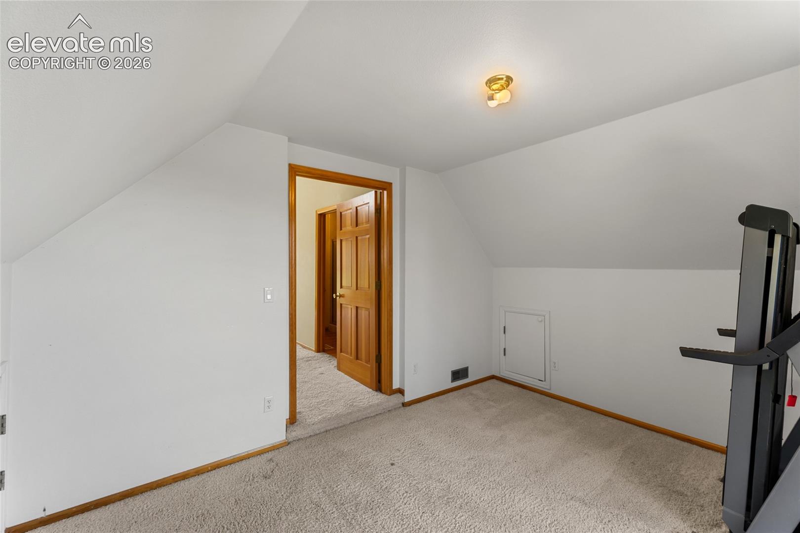 Carpeted room with sloped ceilings and a flush-mount ceiling light