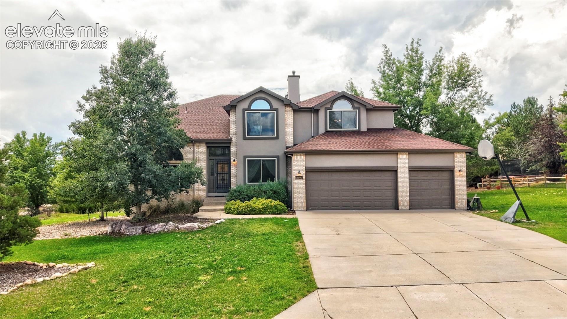 Two-story residence featuring a three-car garage, a concrete driveway, and a shingled roof