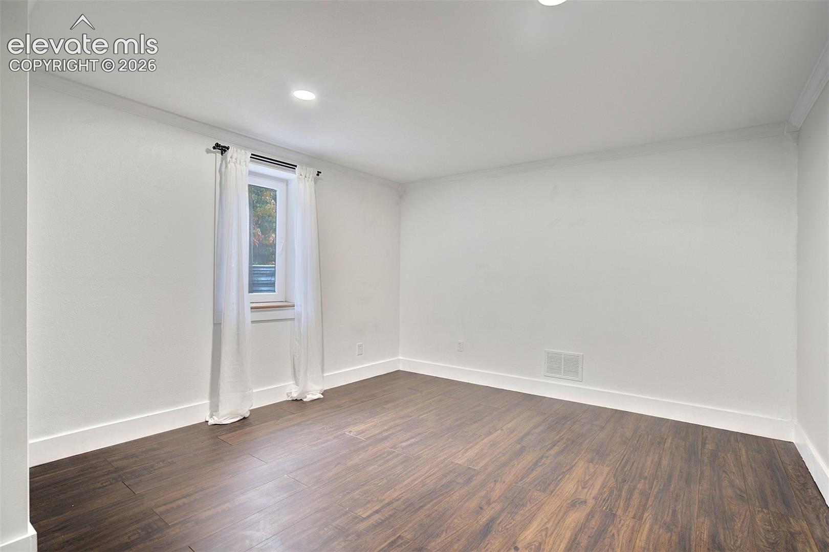 Room featuring dark wood-finish flooring, recessed lighting, and a single window
