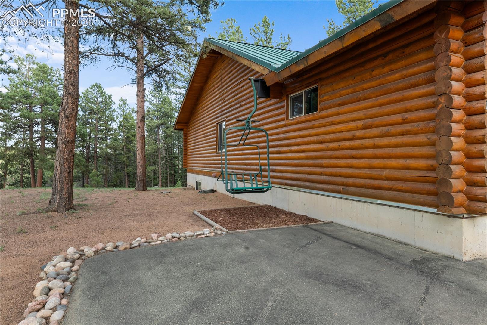 View of property exterior with log exterior, a metal roof, and a patio
