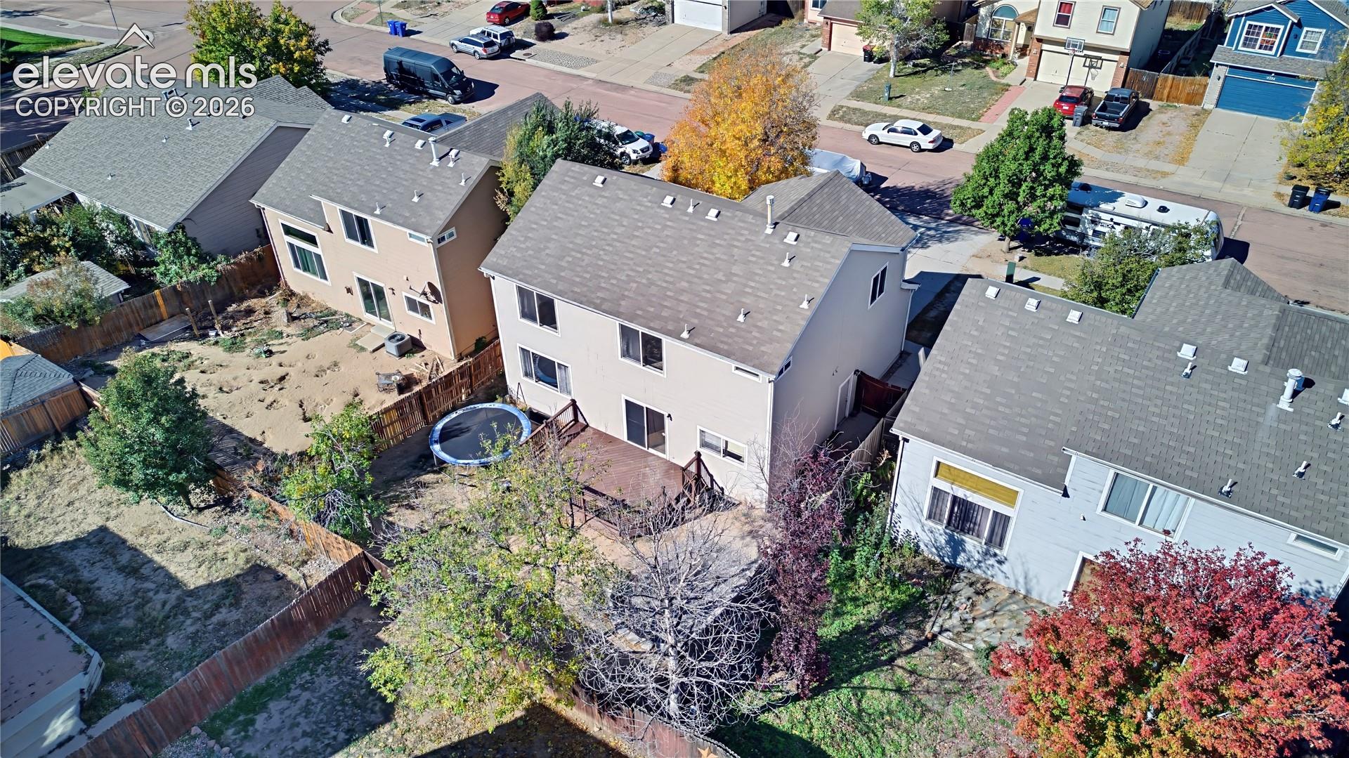 Two-story residence featuring a wood deck, fenced backyard, and shingled roof