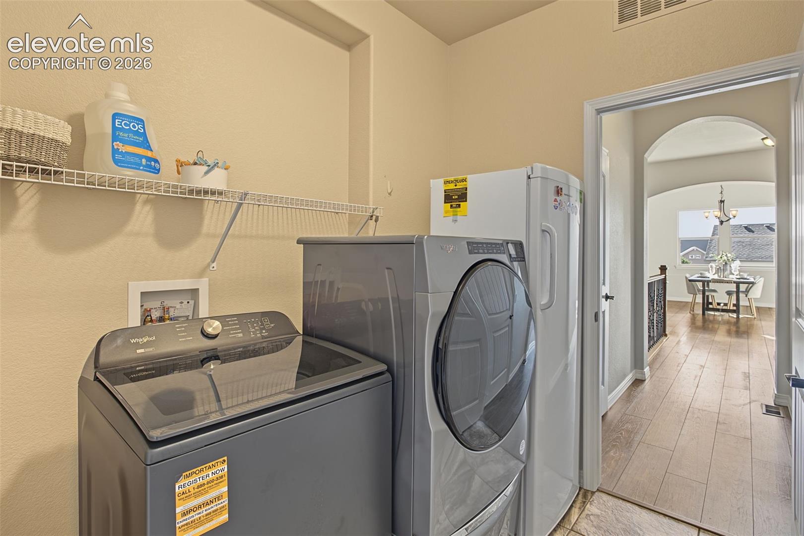 off of the primary bathroom, enter into the Utility room featuring built-in wire shelving and wood-finish flooring
