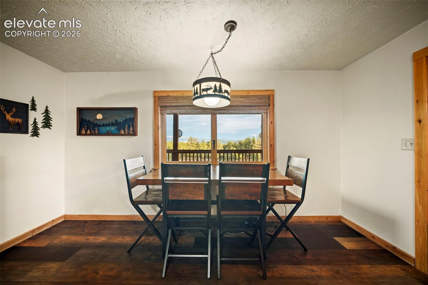 Dining area featuring wood-finish flooring, wood-trimmed windows, and a decorative pendant light fixture