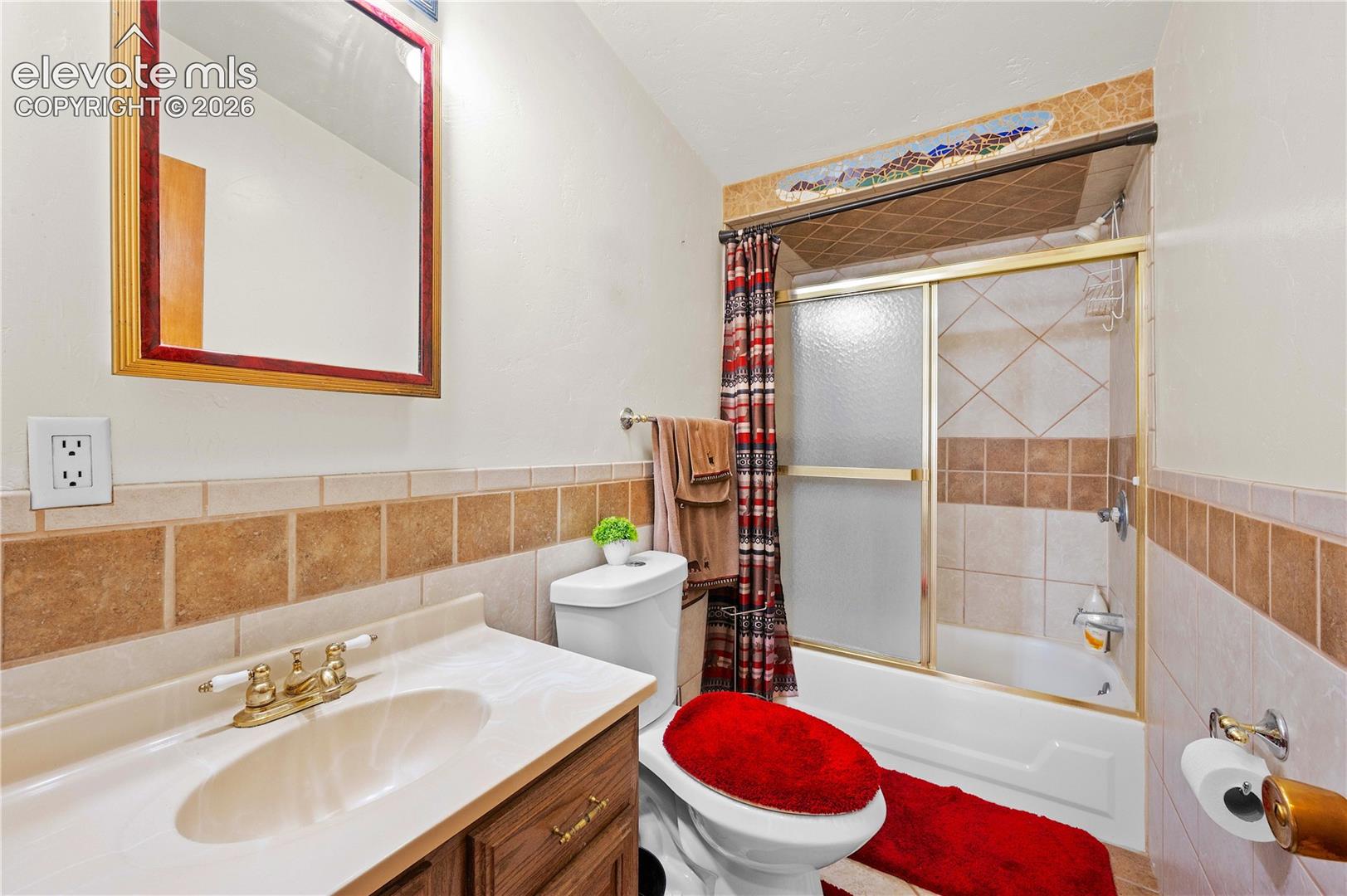 Full bathroom with vanity, toilet, shower / bath combination with curtain, and tile walls