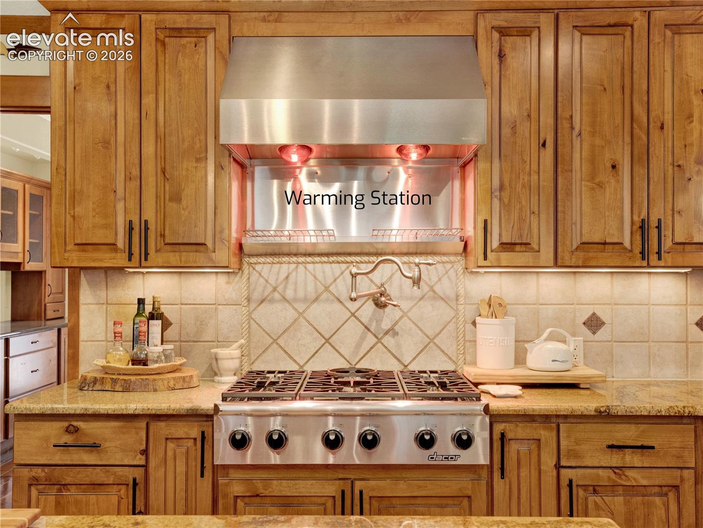 Top of the line dacor stove top with pot filler and warming station above