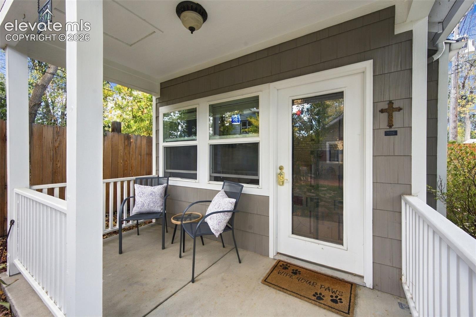 Covered porch featuring shake-style siding, white railing, and a glass-paneled entry door