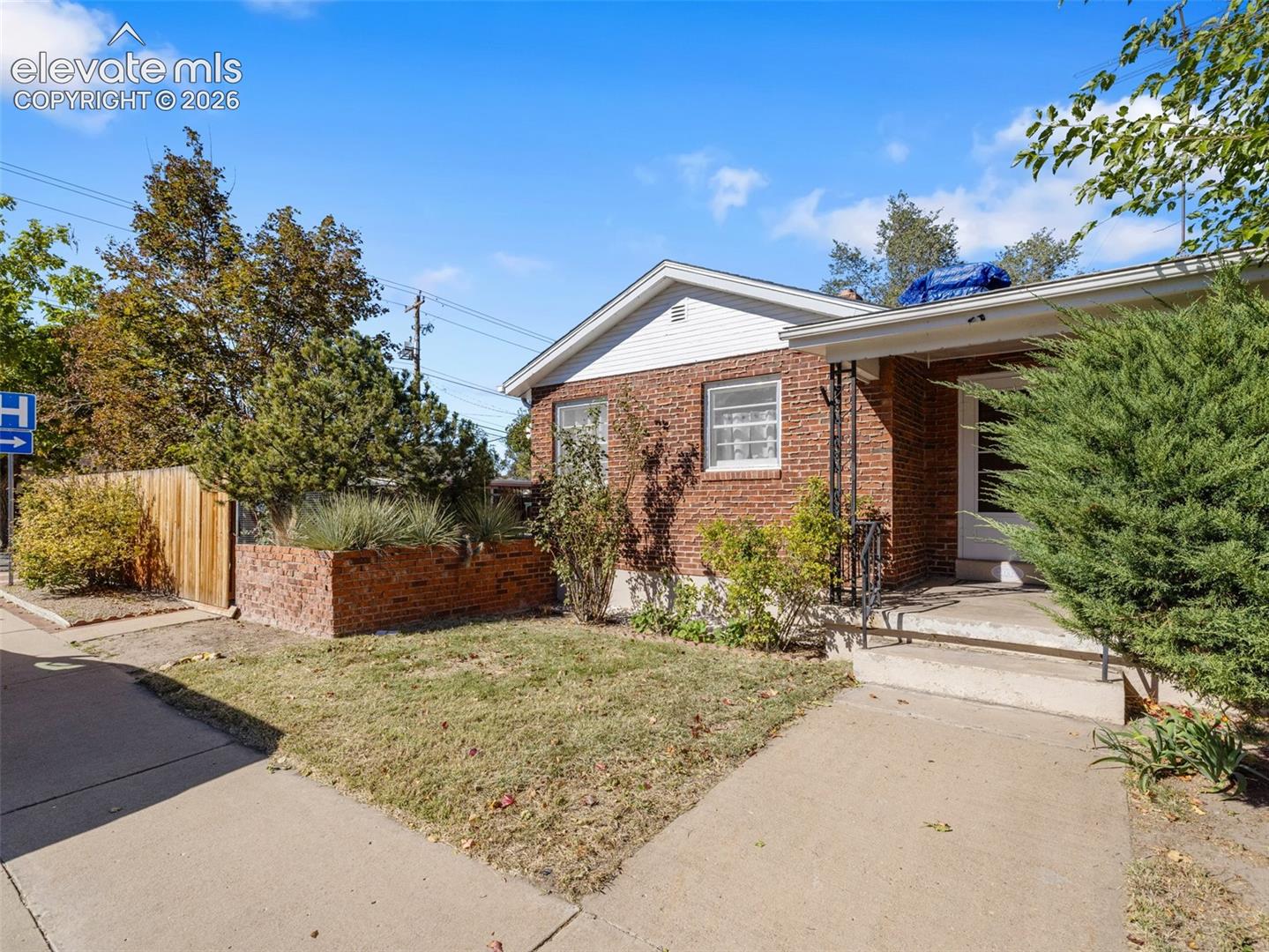 Brick exterior featuring a covered front porch, concrete walkway, and built-in brick landscape planter