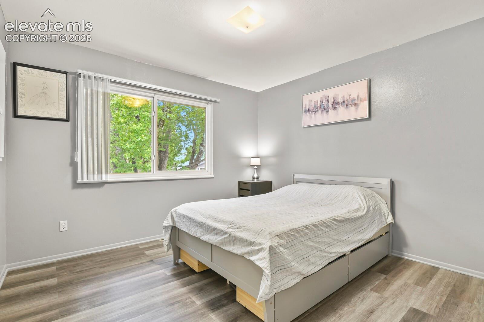 Spacious interior featuring wood-finish flooring, a contemporary window with vertical blinds, and neutral grey wall finishes