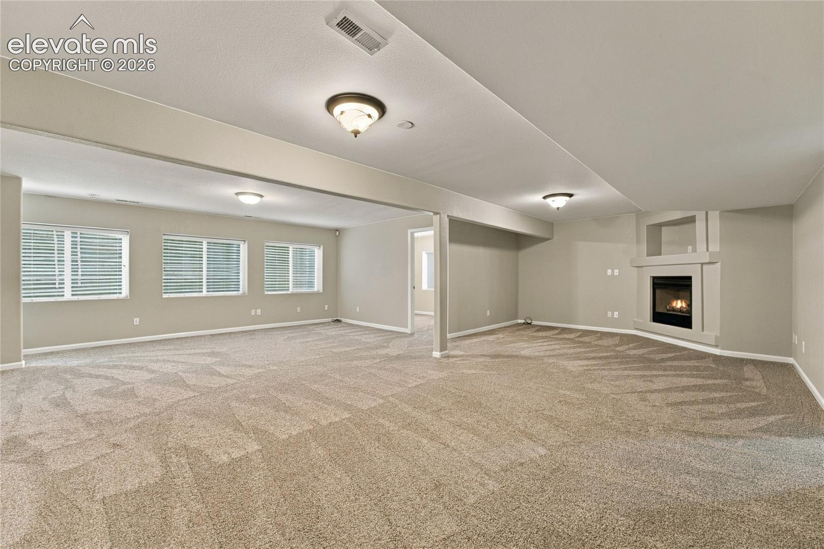 large recreation room in basement with gas fireplace accessing the 3 additional bedrooms and utility area