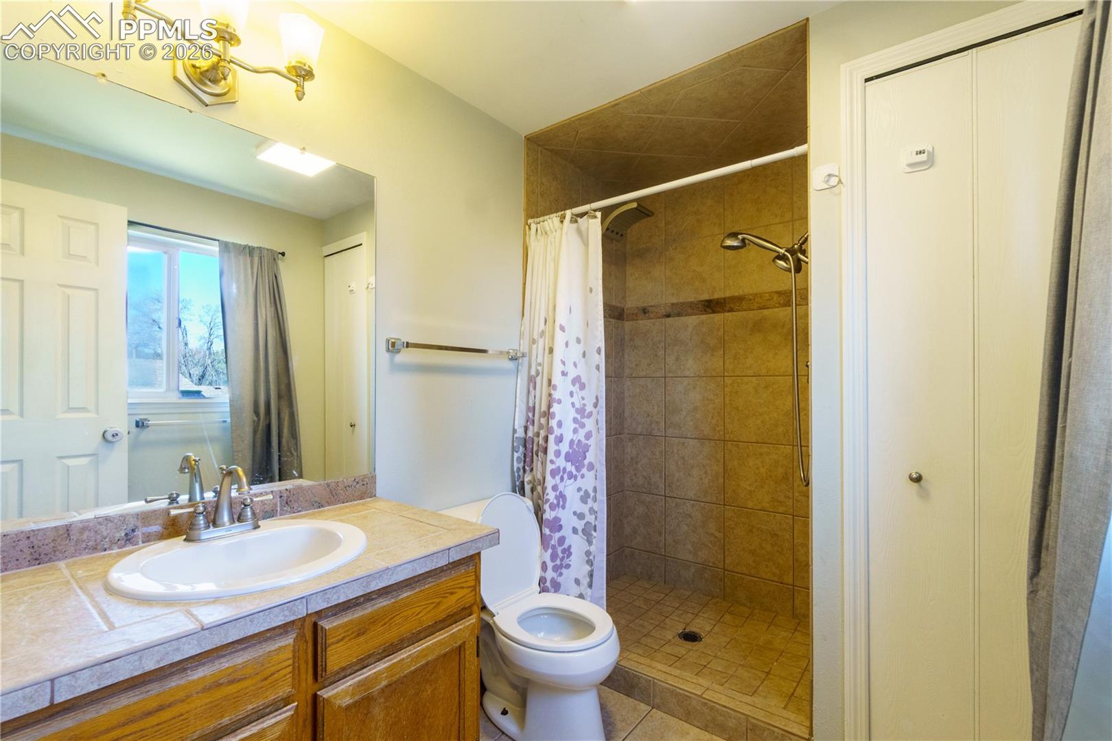 Primary Bathroom featuring tiled shower, vanity, and toilet