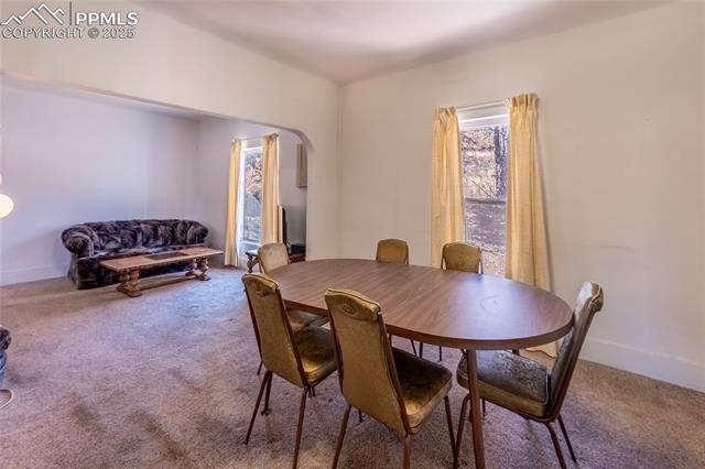 Carpeted dining room with arched walkways and baseboards