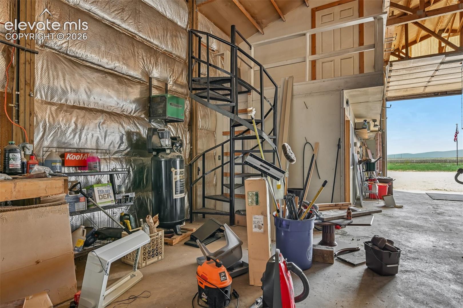 Spacious barn interior featuring exposed wooden rafters and robust concrete flooring