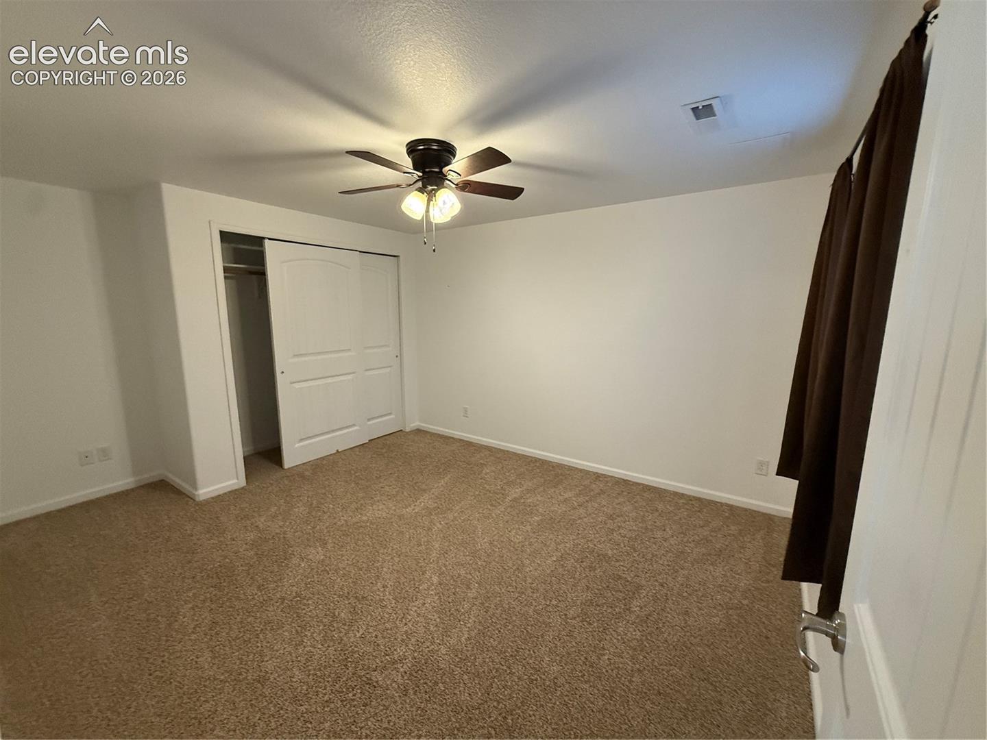 Room featuring wall-to-wall carpeting, ceiling fan with integrated lighting, and a closet with sliding paneled doors