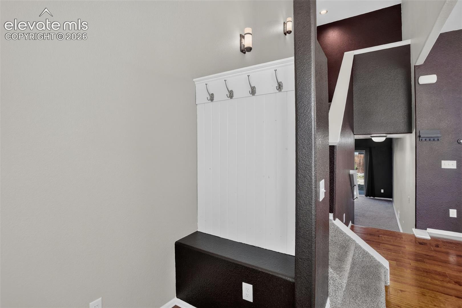 Built-in bench with coat hooks, accent wall finishes, and recessed lighting