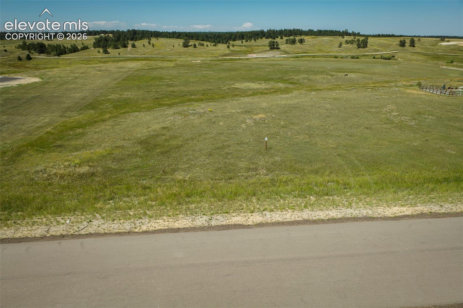 Expansive parcel of open land featuring rolling topography, natural grass coverage, and direct paved road access
