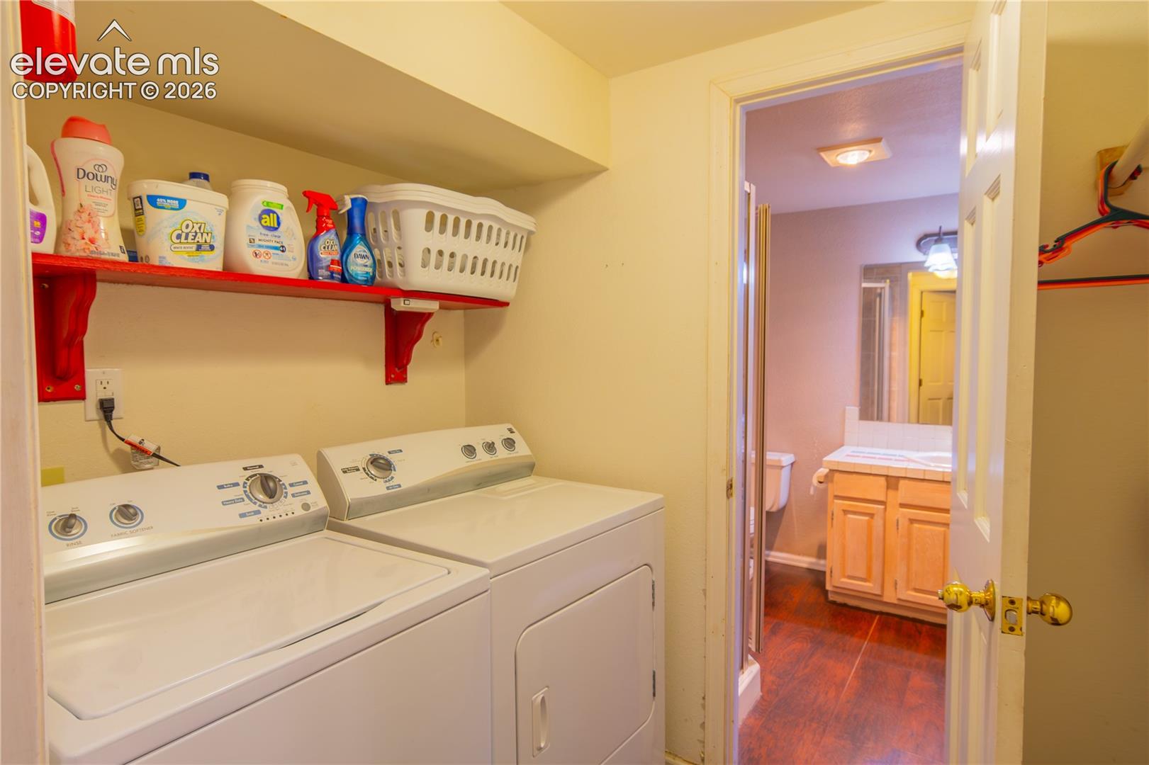 In-unit laundry appliances, built-in shelving, wood-finish flooring in bathroom, bathroom vanity with countertop, and toilet