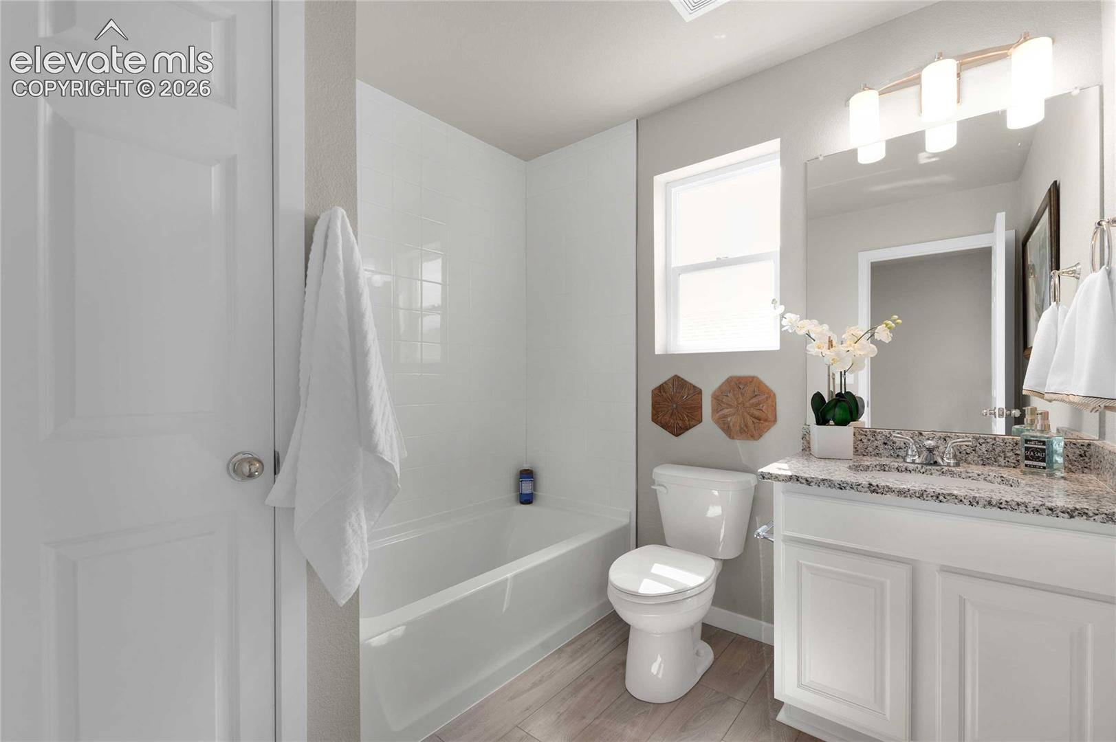 White paneled cabinetry with a stone countertop, an undermount sink, and a framed vanity mirror
*photos of a model home*