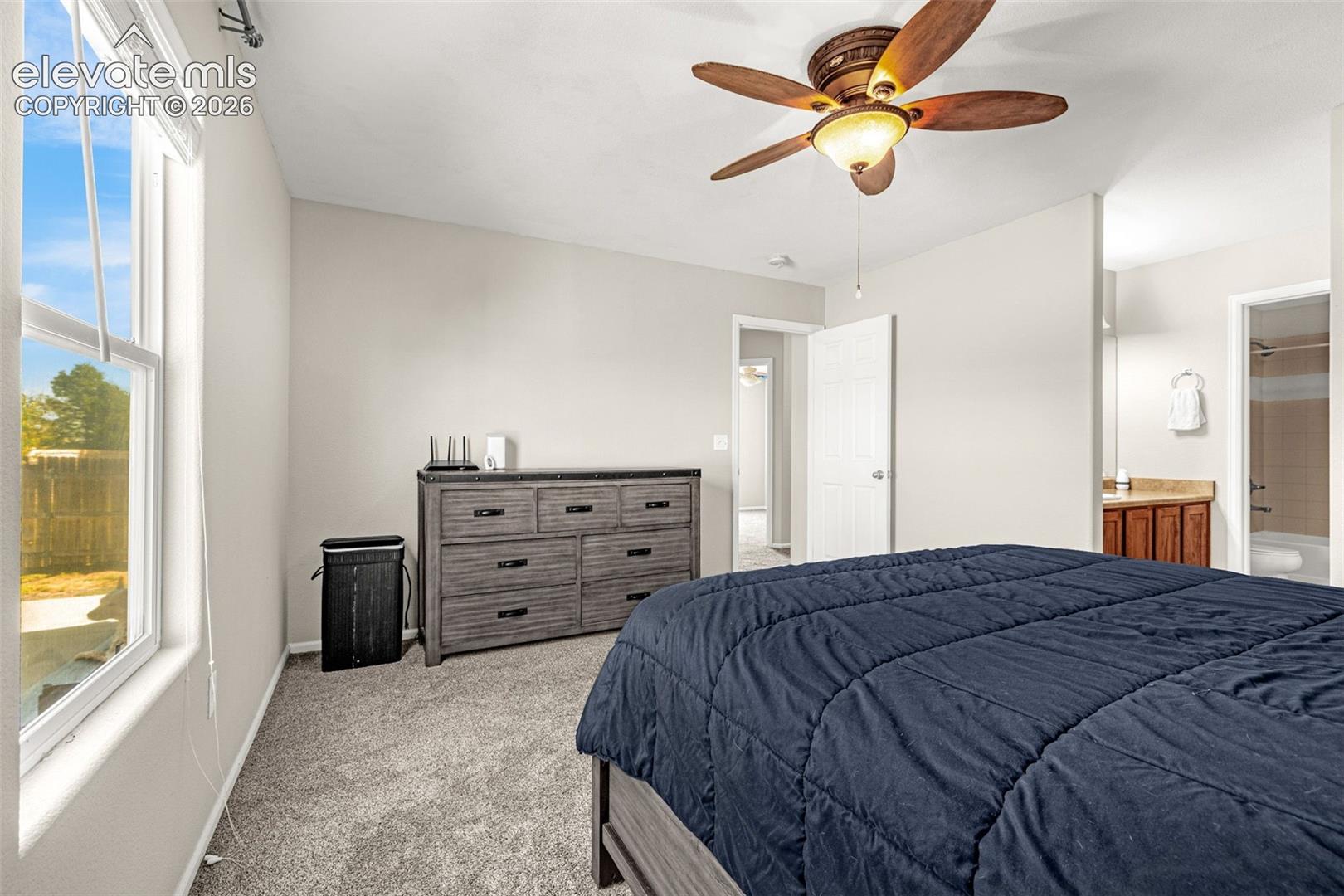 Vaulted ceiling with a ceiling fan, carpeted flooring, and a large window