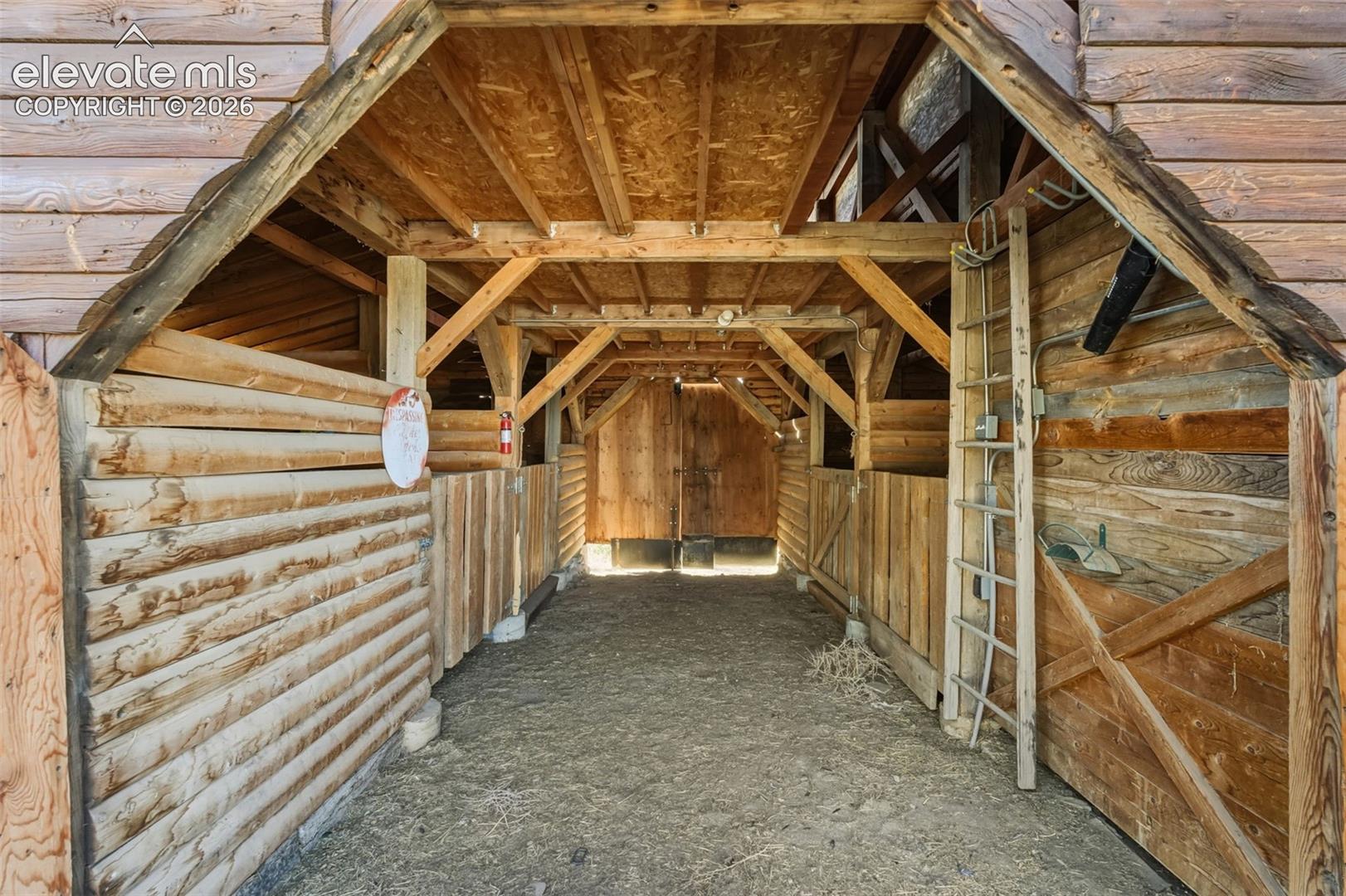Exposed wood beam construction, natural wood plank walls, and a gravel floor