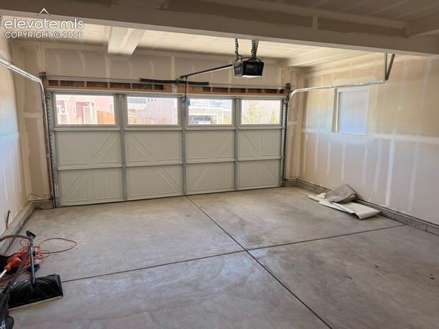Concrete flooring, automatic garage door opener, and a panel-style garage door with integrated windows