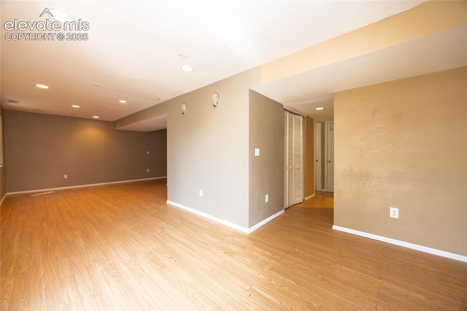 Expansive living area with wood-finish flooring, recessed lighting, and neutral wall tones