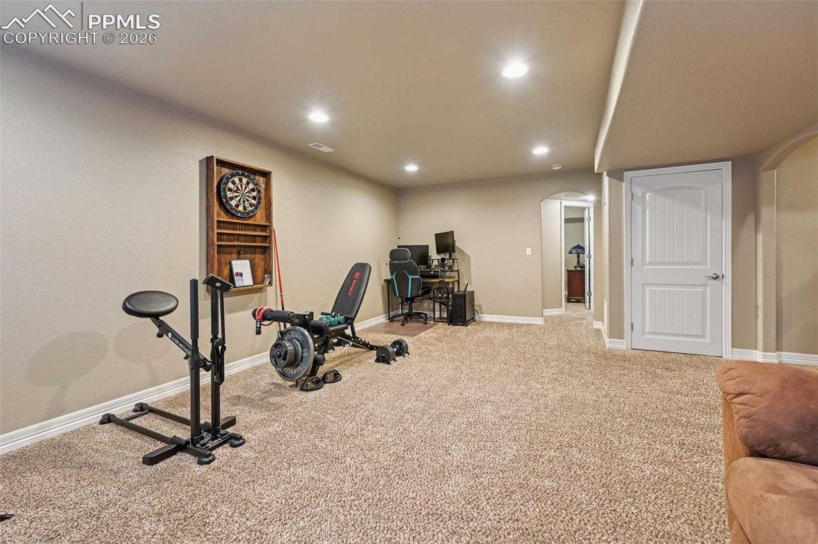 Workout area featuring arched walkways, recessed lighting, and light colored carpet