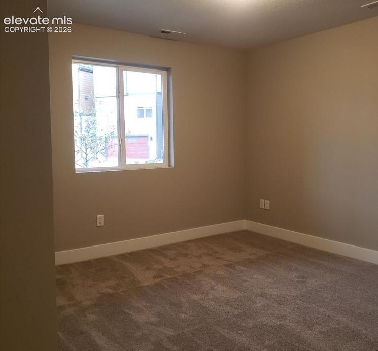 Neutral-toned walls, plush wall-to-wall carpeting, and a double-pane sliding window providing natural illumination