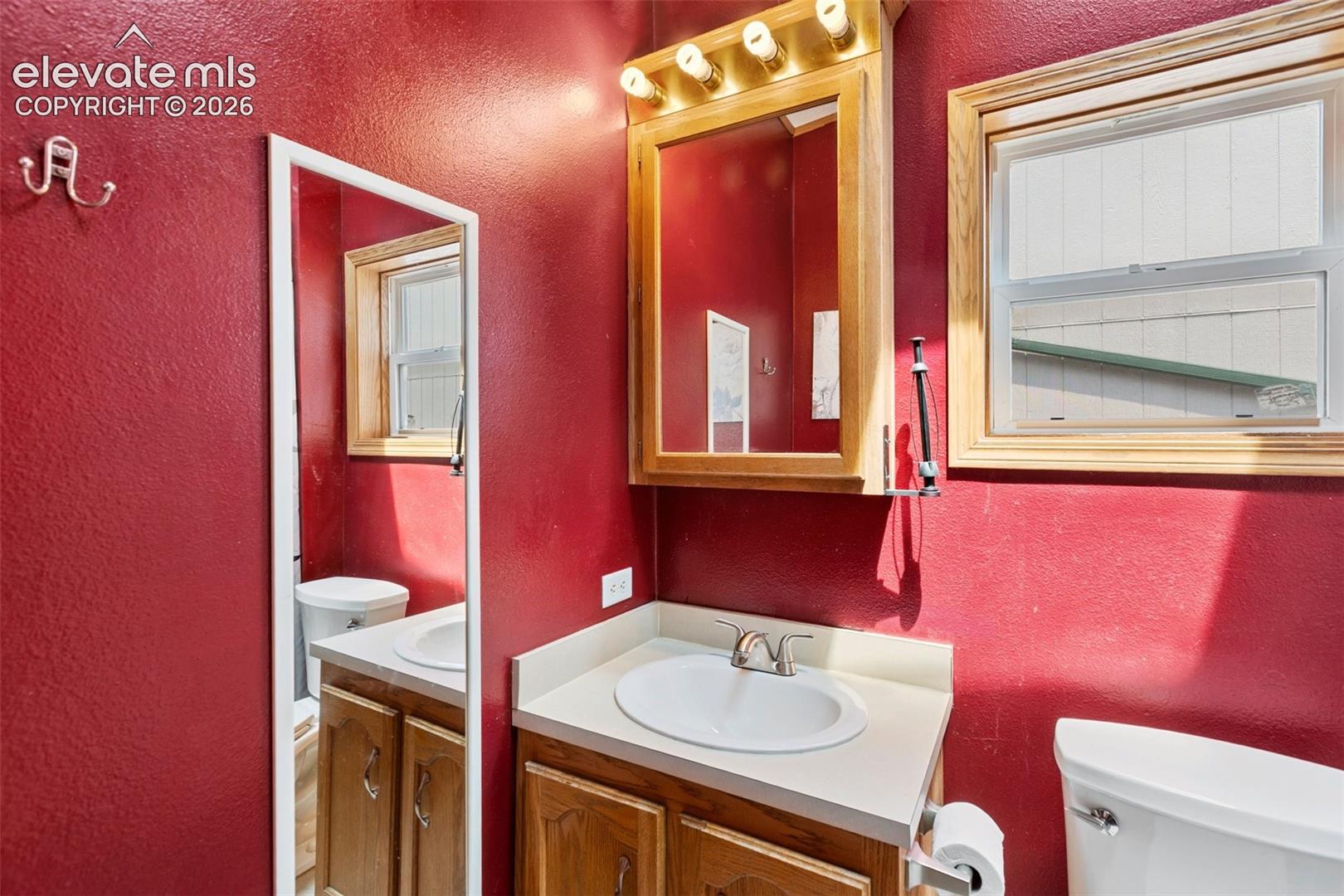 Bathroom featuring a wood-finish vanity with a white oval sink and chrome faucet