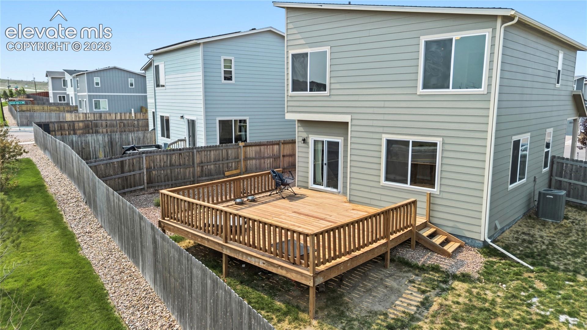 Rear view of home and backyard deck with stairs to the yard.