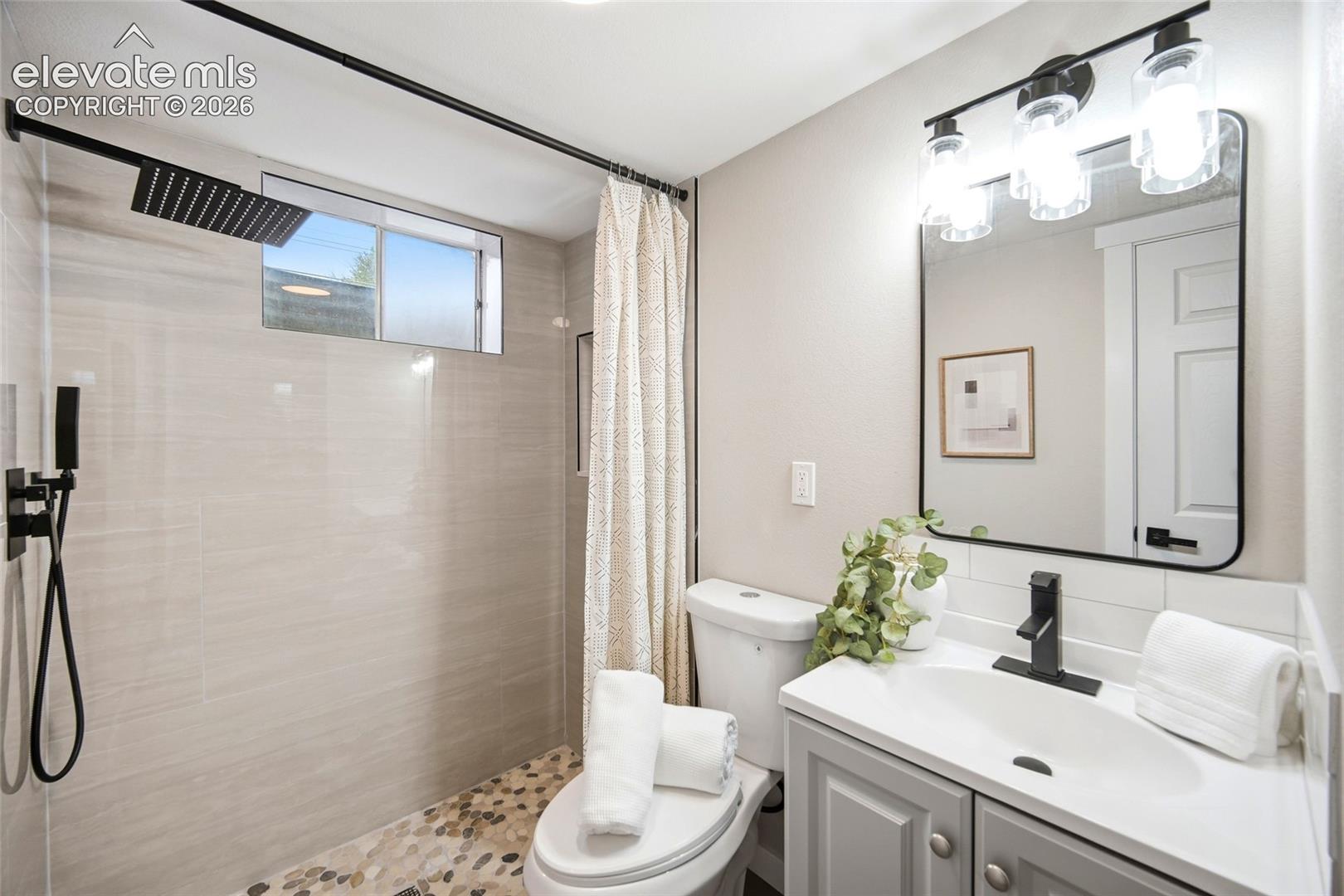Walk-in shower with pebble flooring and matte black fixtures
