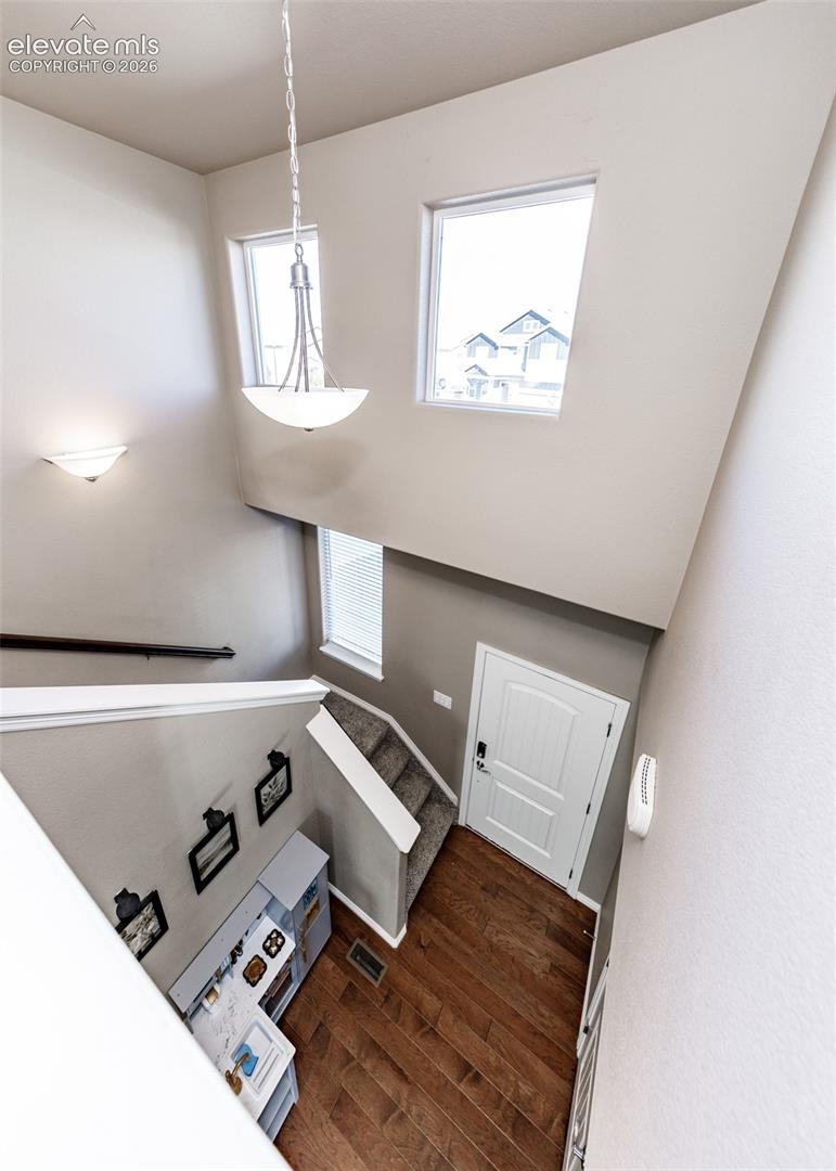 Entryway featuring a two-story ceiling, tall windows, wood-finish flooring, and a multi-tiered pendant light fixture