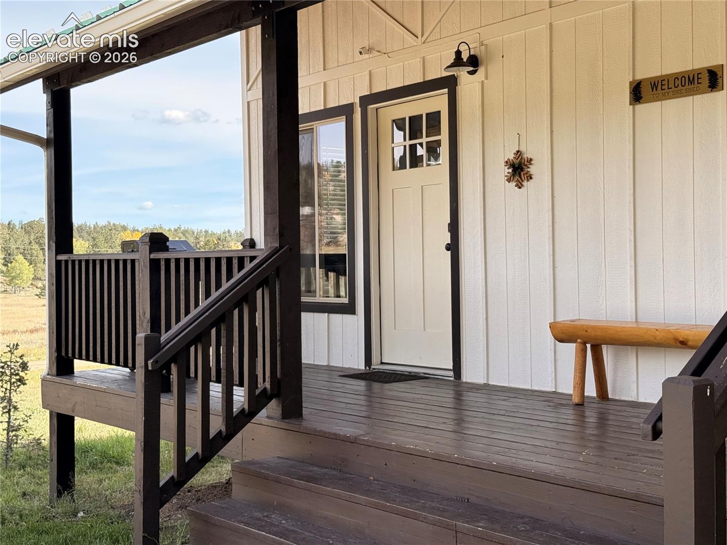 Covered porch with wood flooring, wood railings, and a green roof accent