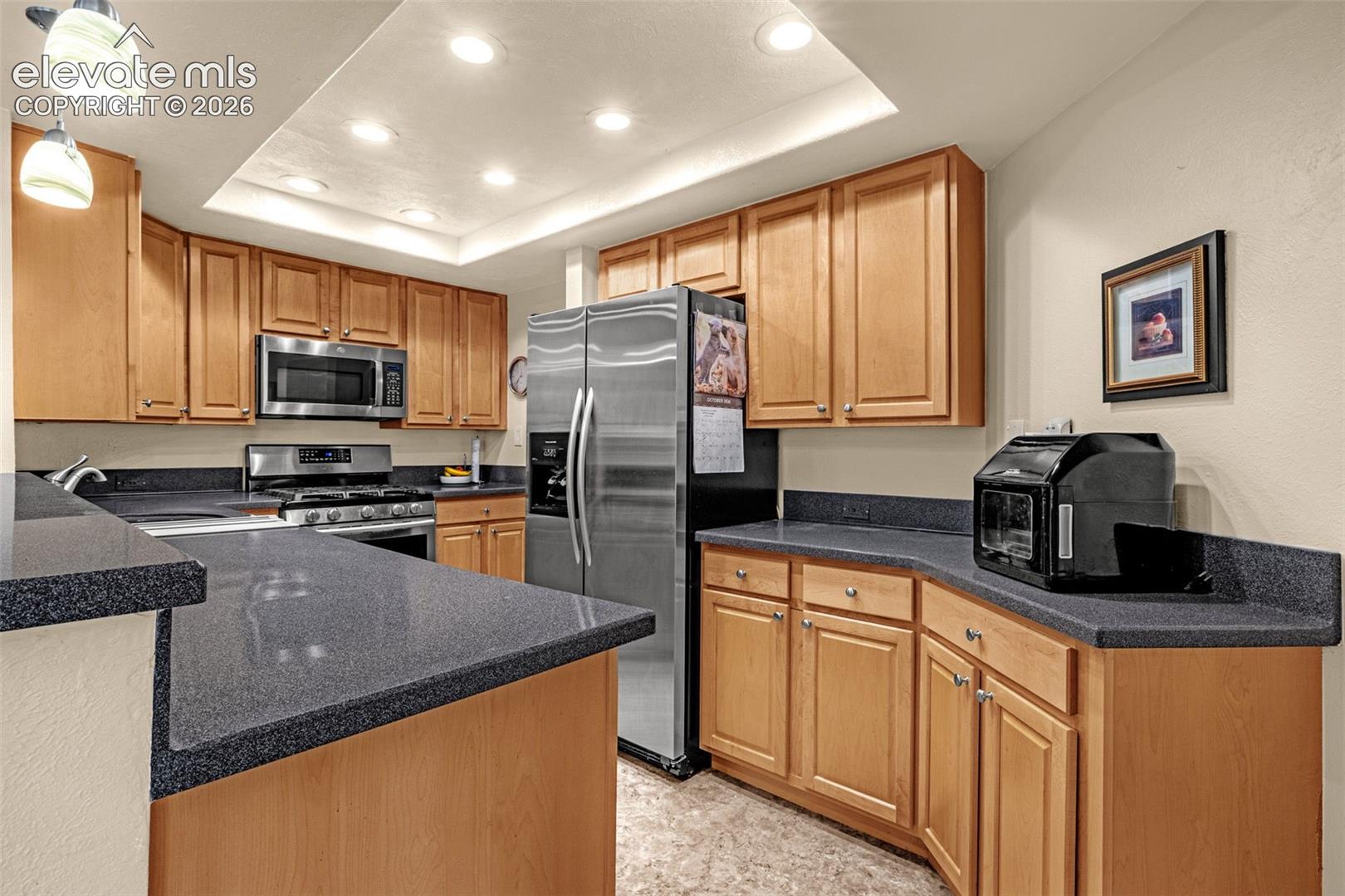 Beautifully updated kitchen with gas stove, curved corner sink, hardwood cabinets and tile floors