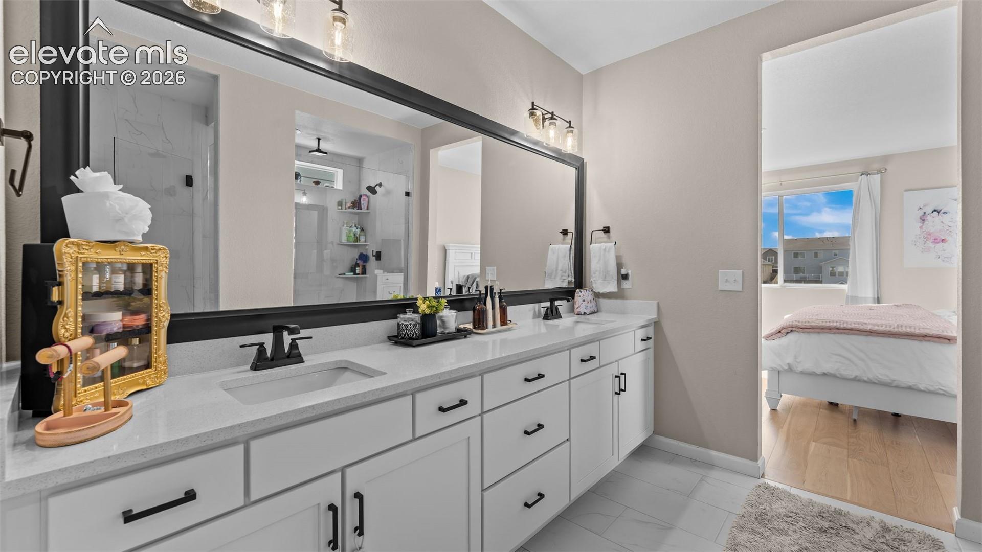 Dual sink vanity with white cabinetry, quartz-finish countertop, and matte black fixtures