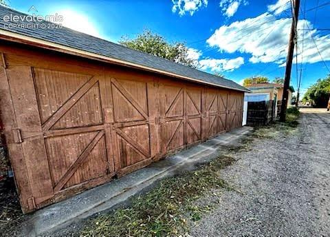 Detached multi-car garage featuring wood-frame carriage-style doors, asphalt shingle roofing, and a concrete foundation