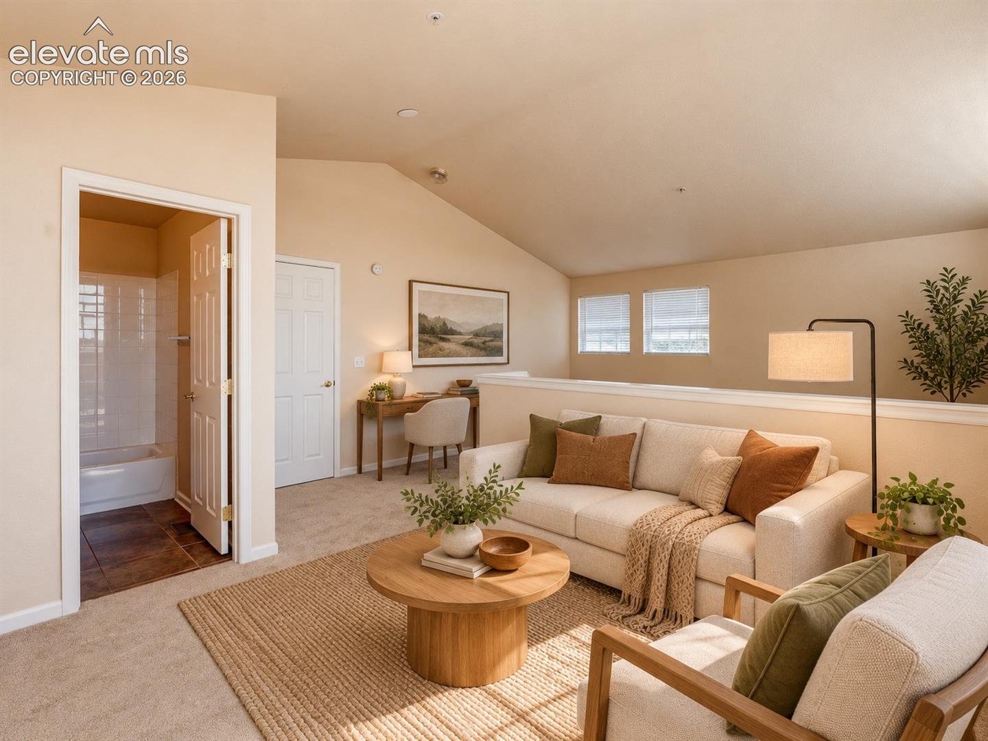 Vaulted ceiling, neutral wall tones, wall-to-wall carpeting, and an en-suite bathroom featuring a tub-shower combination with tiled surround