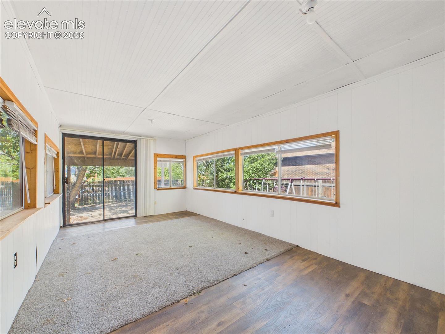 Enclosed sunroom offers a generous footprint with windows on multiple sides, a sliding glass door to the yard, and flexible space for relaxing, hobbies, or entertaining.