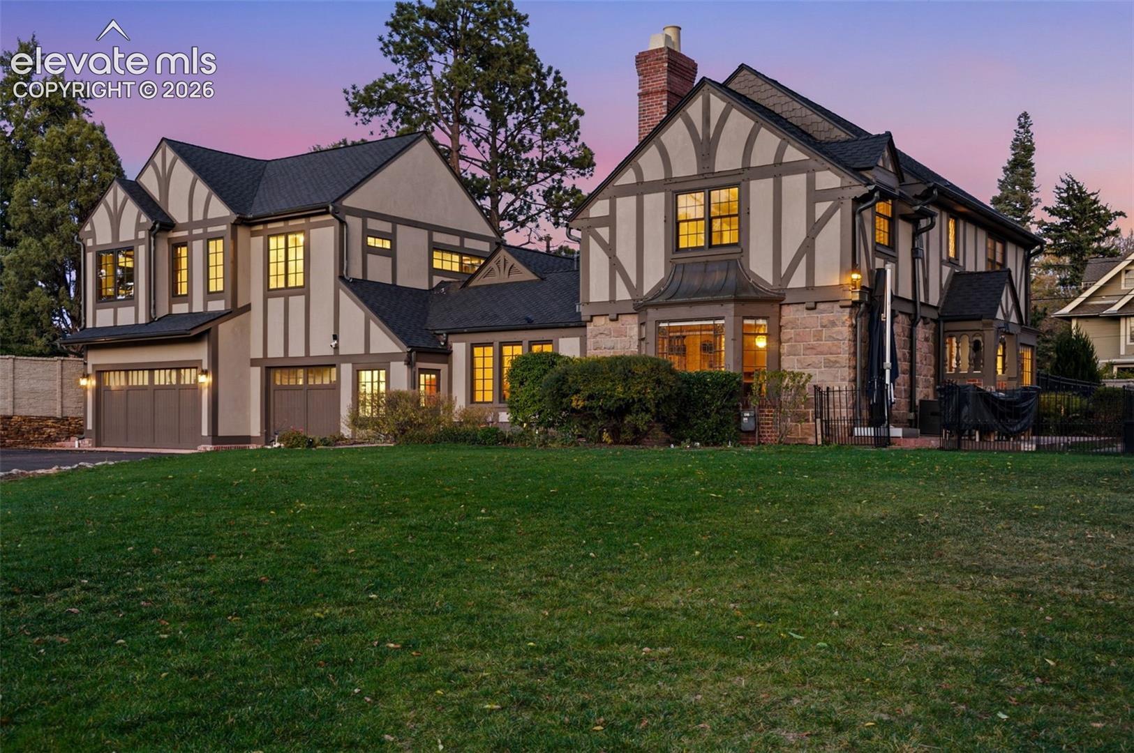 Tudor-style exterior featuring half-timbered detailing, stone masonry, a multi-gabled roofline, and a multi-car garage