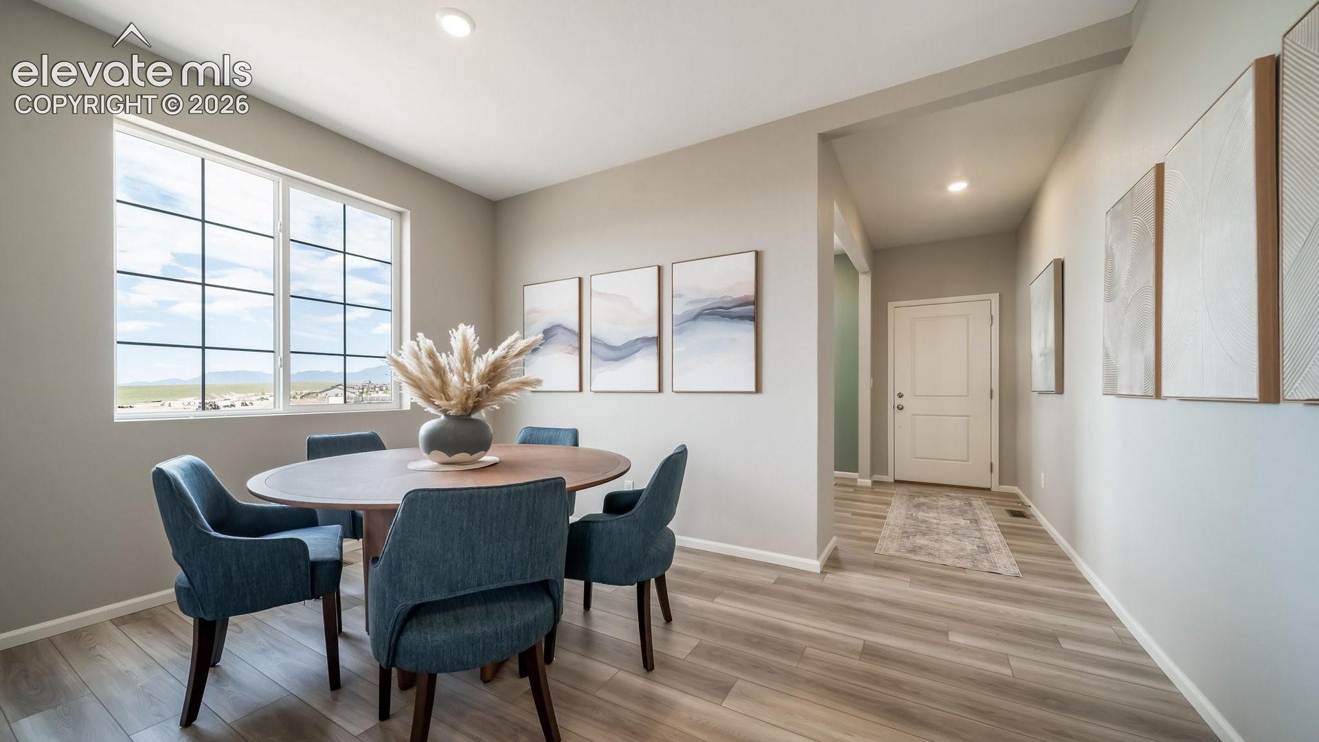 Bright dining area featuring a large grid-pattern window, wood-finish flooring, recessed lighting, and a neutral color palette
Photos of a model home