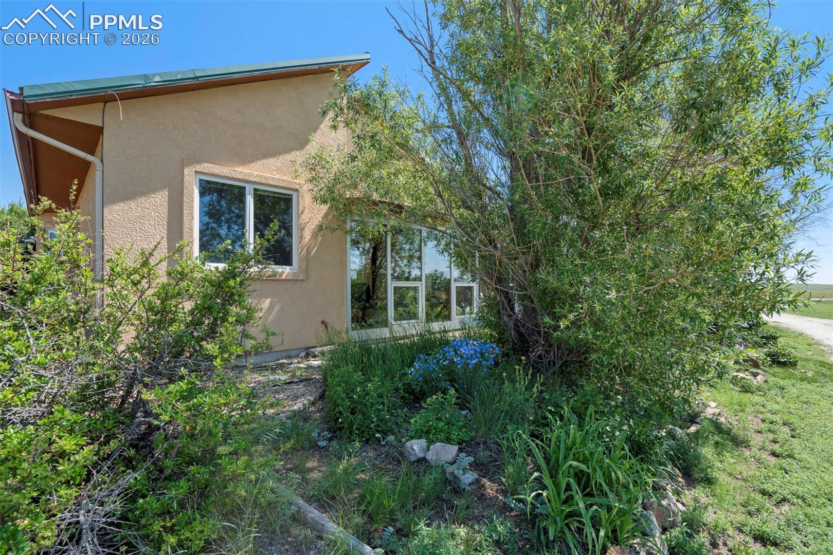 Sloping roofline with green metal roofing and stucco exterior