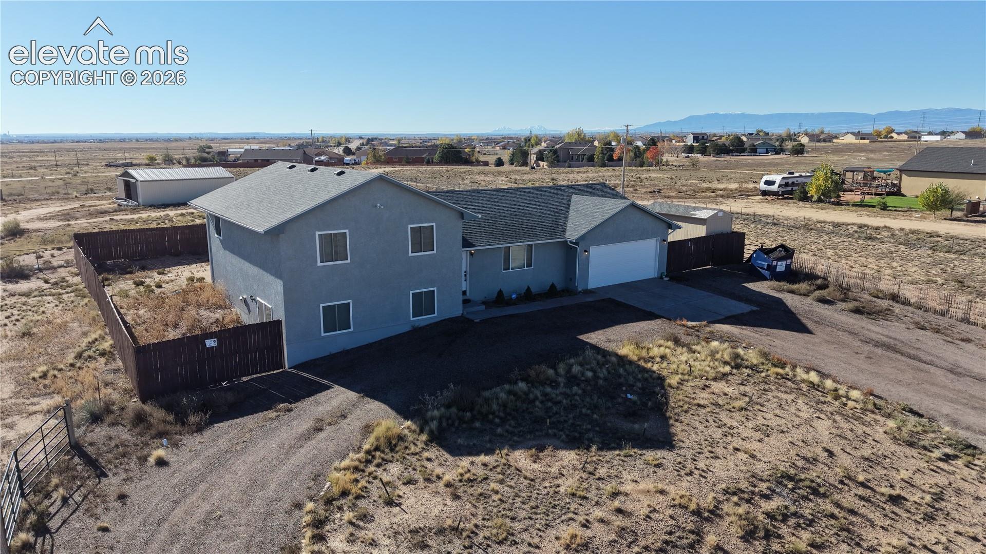 Residence featuring a stucco exterior, attached garage, enclosed rear yard, and mountain backdrop