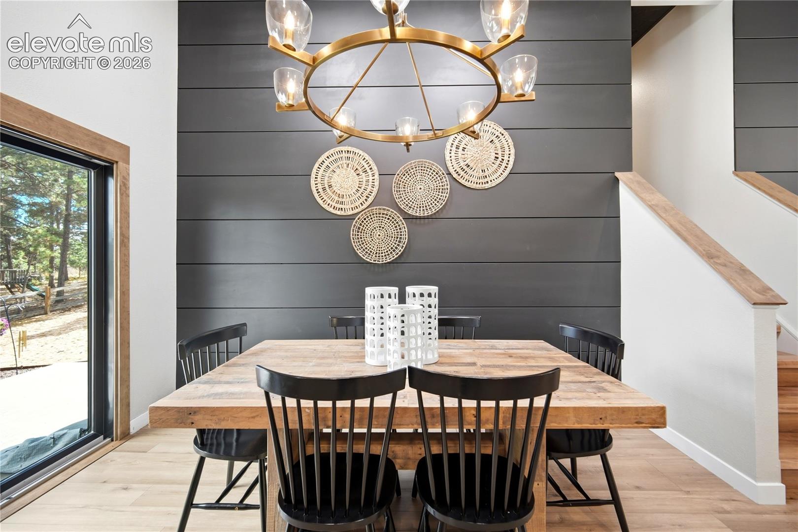 Charcoal horizontal shiplap accent wall, oversized gold-finish multi-light chandelier, and wood-finish flooring